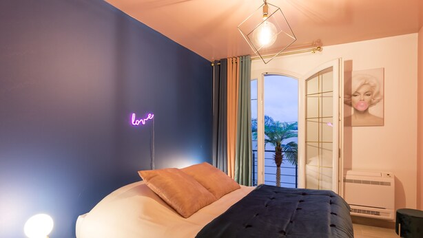 A modern bedroom with a bed, a neon sign, a bedside lamp, and a view of the outdoors. - Marilyn Monroe Suite - 4P with Private Jacuzzi (Montry)