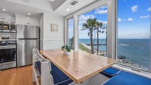 Eine Küche mit Holztisch und blauen Sitzkissen mit Blick auf Strand und Meer.