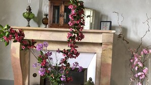 Une cheminée décorée de fleurs roses, un meuble en bois et des appliques murales.