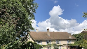 Une maison avec un toit en tuiles et un jardin agrémenté d’un bac à fleurs en béton.