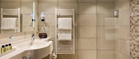 A modern bathroom with a sink, mirror, towel rack, and shower.