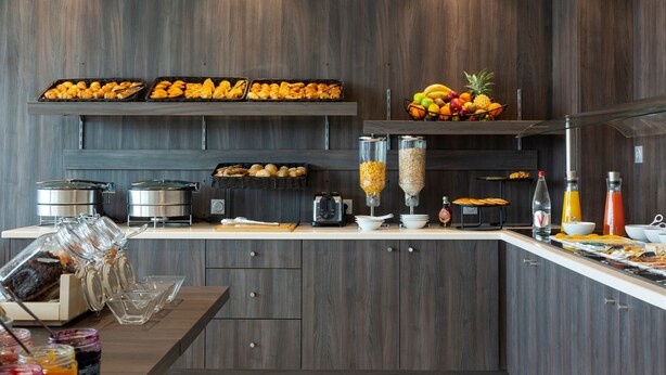 Una cocina moderna con armarios de madera, un frutero y diferentes alimentos.