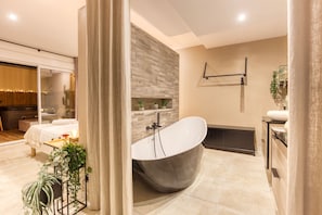 Un baño moderno con una bañera independiente, cabina de ducha con paredes de vidrio y tocador con lavabo.