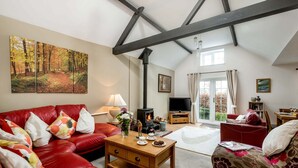 A spacious living room with a high ceiling, a fireplace, a television, and a dining area. - New Forest Cottages. (Godshill)