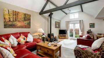 A spacious living room with a high ceiling, a fireplace, a television, and a dining area.