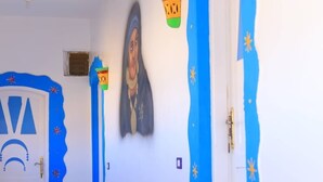 Un pasillo con paredes azul y blanco, una puerta de diseño único y un cuadro colgado en la pared.