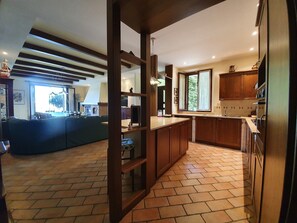 A modern kitchen with wooden cabinets, a large island, and a dining area with a sofa.
