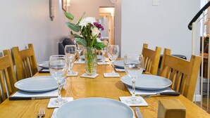 A dining table set with plates, glasses, and cutlery, surrounded by wooden chairs. - 3 bedroom accommodation in Sheringham (Sheringham)
