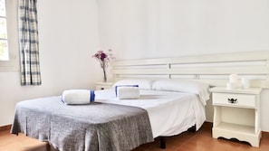 A neatly arranged bedroom with a bed, bedside tables, and a window with curtains.