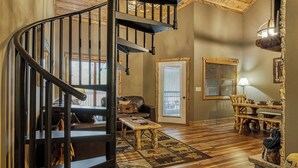 Un salón amplio con una escalera de madera, chimenea, una mesa de comedor y una zona de estar acogedora.