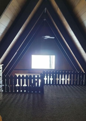 An attic room with a sloped ceiling, a window, and a decorative railing.
