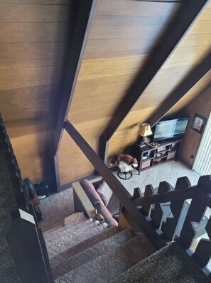 Staircase leads to a cozy landing with a TV and a friendly dog.