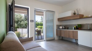 Een moderne keuken met een schuifdeur naar een balkon, een bank en een aanrecht met keukenapparatuur.