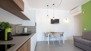 Een moderne keuken met een ingebouwde kookplaat, een koffieapparaat en een eethoek met een tafel en stoelen.