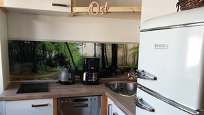 Een kleine keuken met een vaatwasser, een koffiezetapparaat en een koelkast.