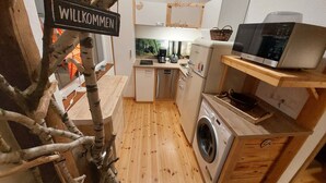 Een kleine keuken met een wasmachine, een magnetron en een koffiezetapparaat.