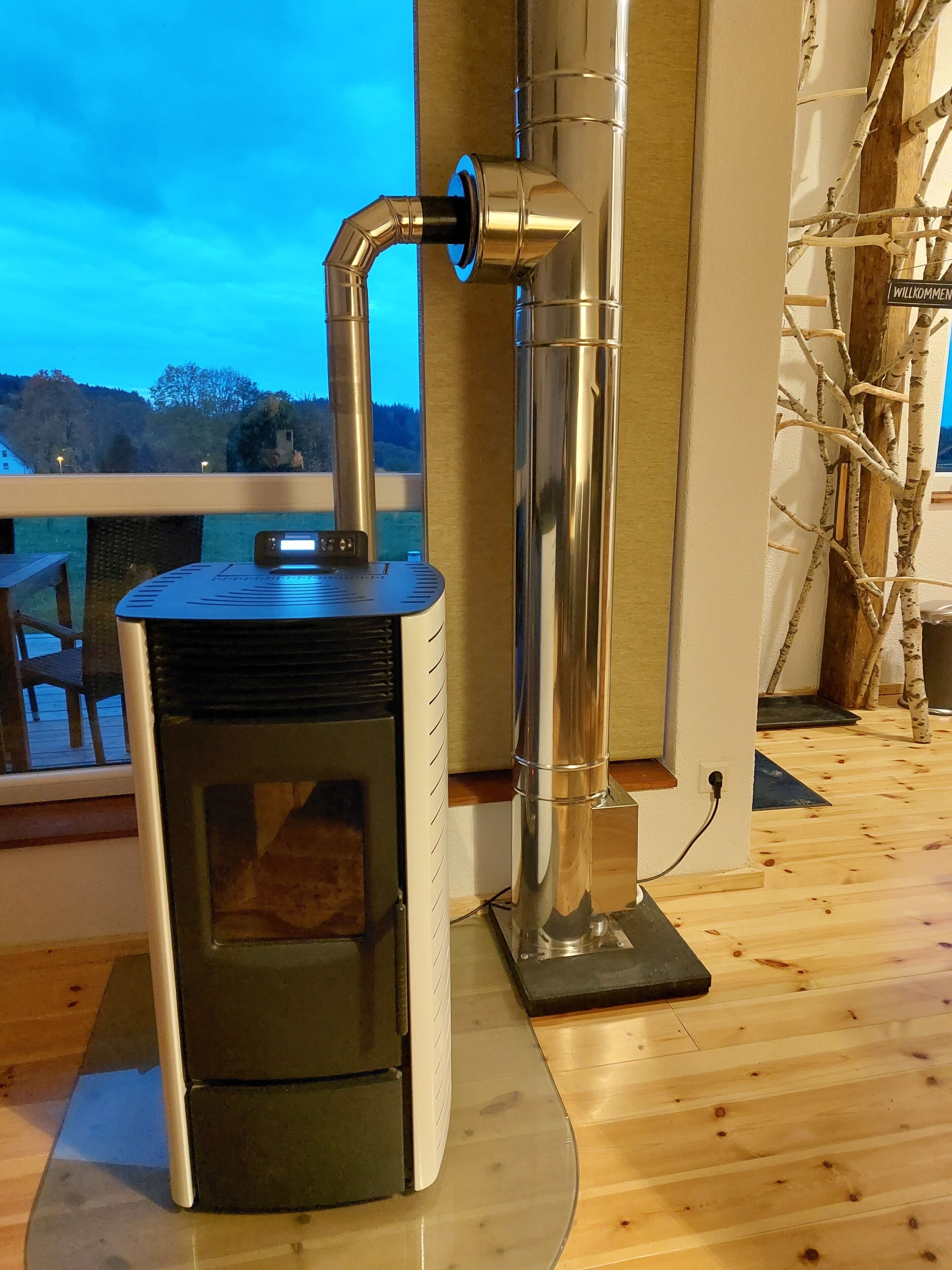 Un poêle à bois avec une cheminée, une fenêtre donnant sur un paysage magnifique et une terrasse en bois.