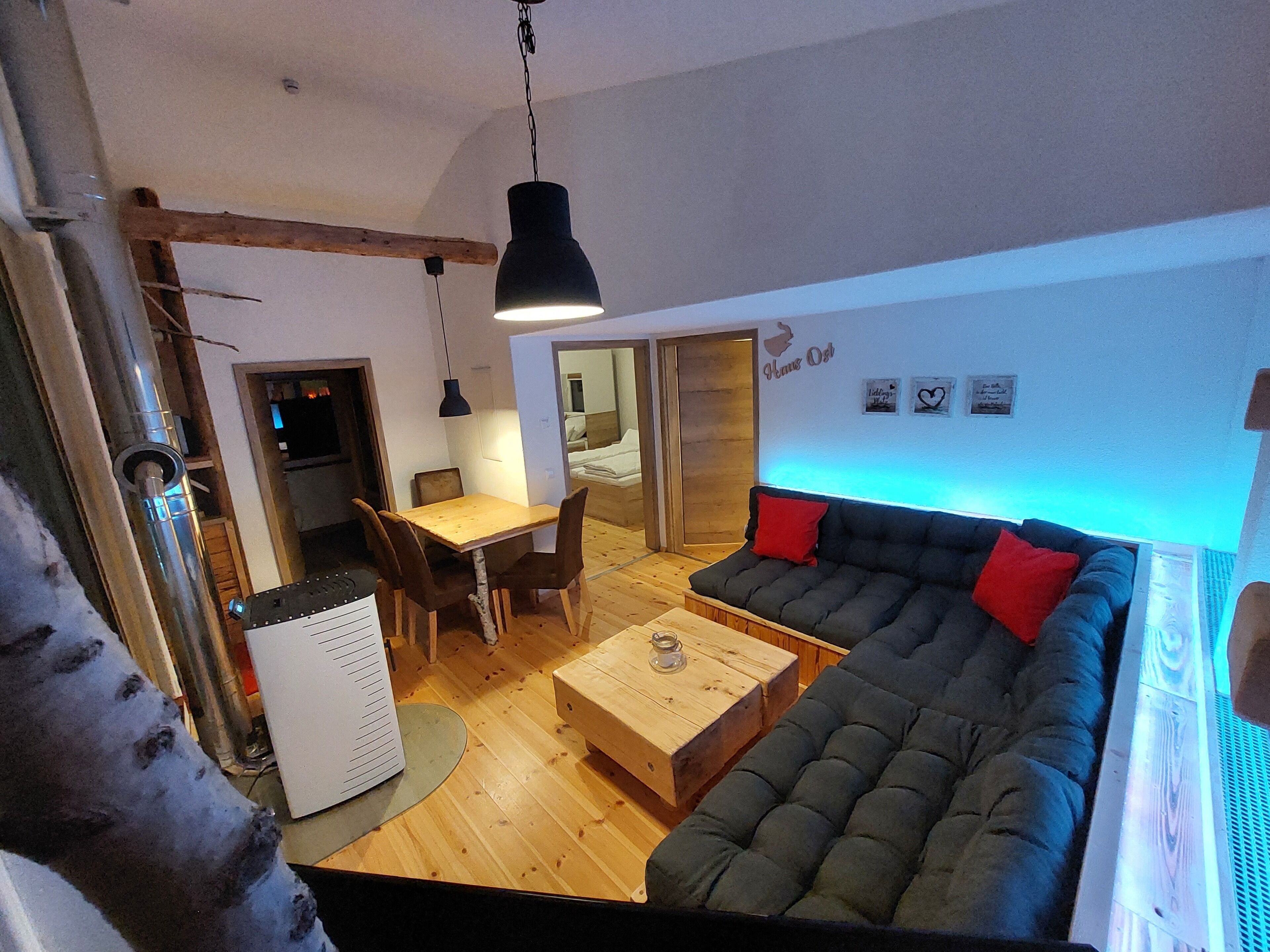 A cozy living area with a sofa, a dining table, and a kitchen in the background.