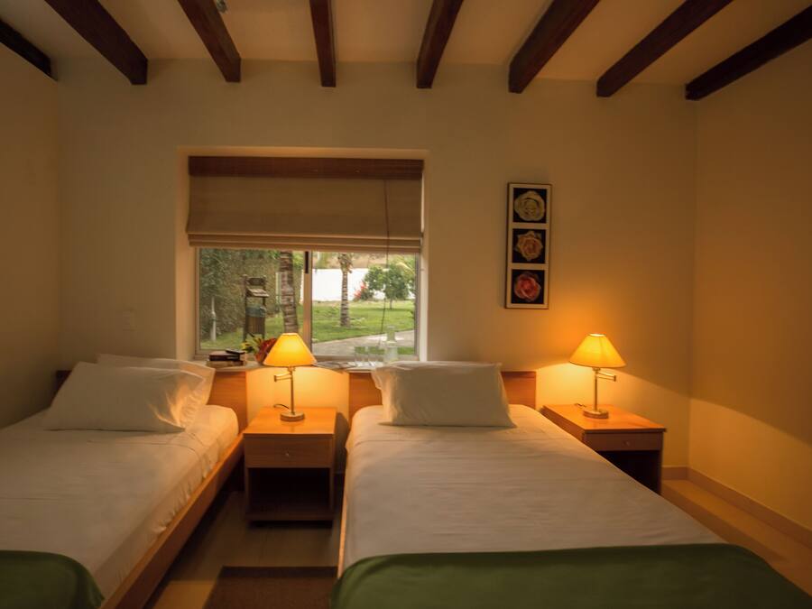 Habitación de hotel con dos camas individuales, lámparas de noche, una ventana con vistas y un cuadro en la pared.
