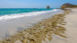 A beach with clear blue water, a rocky outcrop, and a sandy shoreline. - Hosteria del Parque Machalilla - Los Frailes (Machalilla)