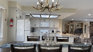 A modern kitchen with white cabinets, a central island, and a chandelier. -  Newly remodeled 3 bedroom home located near Yosemite and bass lake (Oakhurst)