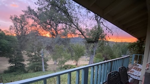 A wooden deck with a railing, a table, and two chairs. -  Newly remodeled 3 bedroom home located near Yosemite and bass lake (Oakhurst)