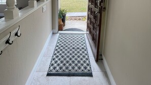 A hallway with a white door, a patterned rug, and a wall-mounted picture holder. -  Newly remodeled 3 bedroom home located near Yosemite and bass lake (Oakhurst)