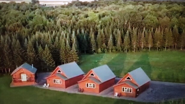 A cluster of red cabins with sloped roofs, surrounded by dense forest and mountains in the background. - Luxury Cabin #2 (Mars Hill)