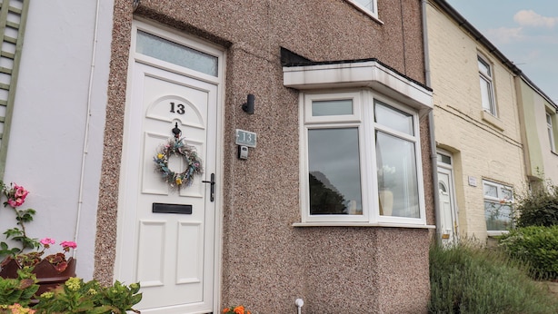 A house with a white front door, number 13, and a small garden with potted plants. - North Terrace (Saltburn-by-the-Sea)