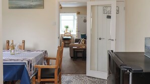 A dining area with a table set for two, a chair, and a small table with a lamp. There is a door with a sign that reads "Gone". - North Terrace (Saltburn-by-the-Sea)