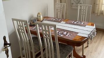 A dining area with a wooden table, white chairs, and a floral border on the wall.