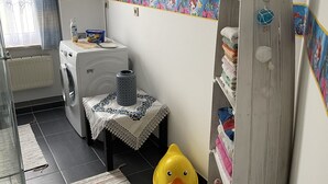 A laundry room with a washing machine, drying rack, and a small table with a decorative tablecloth. - Colorful city on the Elde 2 (Grabow)