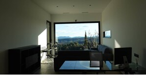 Una sala de estar moderna con un ventanal grande, un sofá, una mesa de centro y un televisor de pantalla plana.