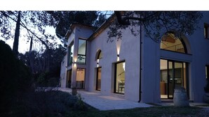 Una casa moderna de dos pisos con ventanas grandes y un patio cubierto.