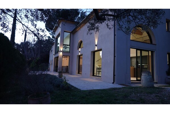 A modern two-story house with large windows and a covered patio area.