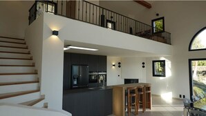 Amplia sala de estar con cocina, comedor y balcón con vistas.