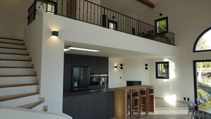 A spacious living area with a kitchen, a dining area, and a balcony with a view. - Secluded villa with heated pool and views of vineyards and sea (Figagnaire)