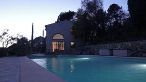 Una casa moderna con piscina, muro de piedra y entrada arqueada.