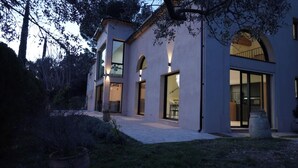 A modern two-story house with large windows and a covered patio area. - Secluded villa with heated pool and views of vineyards and sea (Figagnaire)