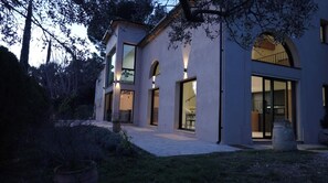 Une maison moderne à deux étages, dotée de grandes fenêtres et d’un patio couvert.