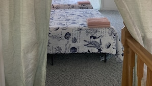 A room with a bed, a wooden headboard, and a window with curtains. - Mermaid's and Mutts Retreat - Beach Front, Pet Friendly, Wi-Fi, Off-Street Park (Norfolk)