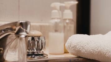 A bathroom sink with running water, soap dispensers, and a white towel.