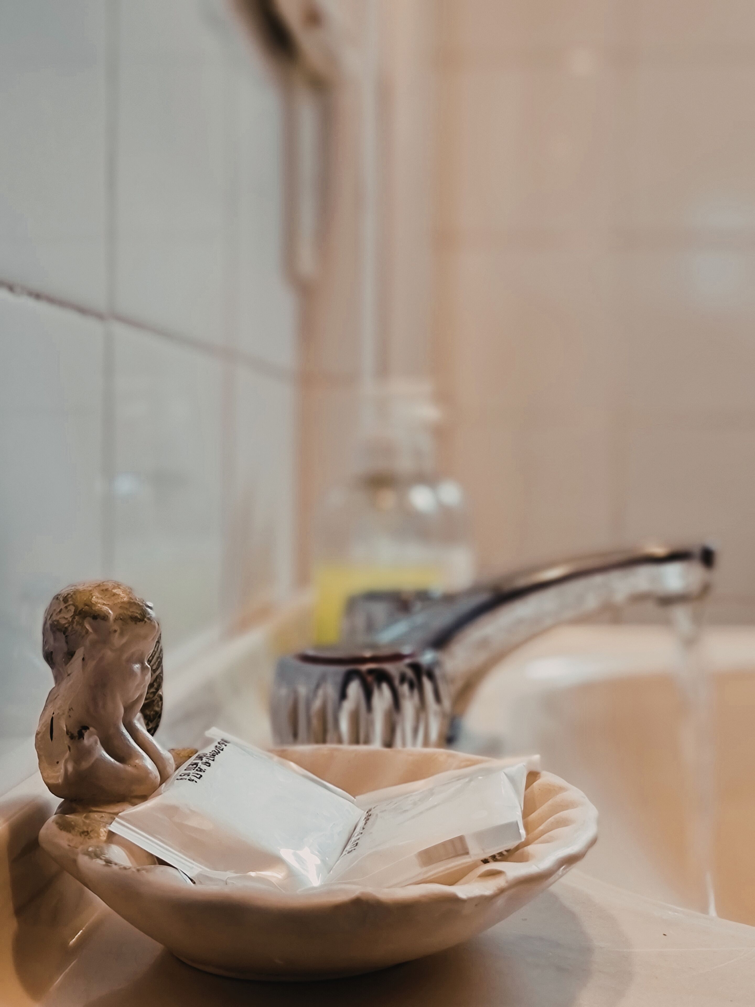 Un lavandino da bagno con una vasca in ceramica, contenente un fazzoletto e una bottiglia di sapone per le mani.