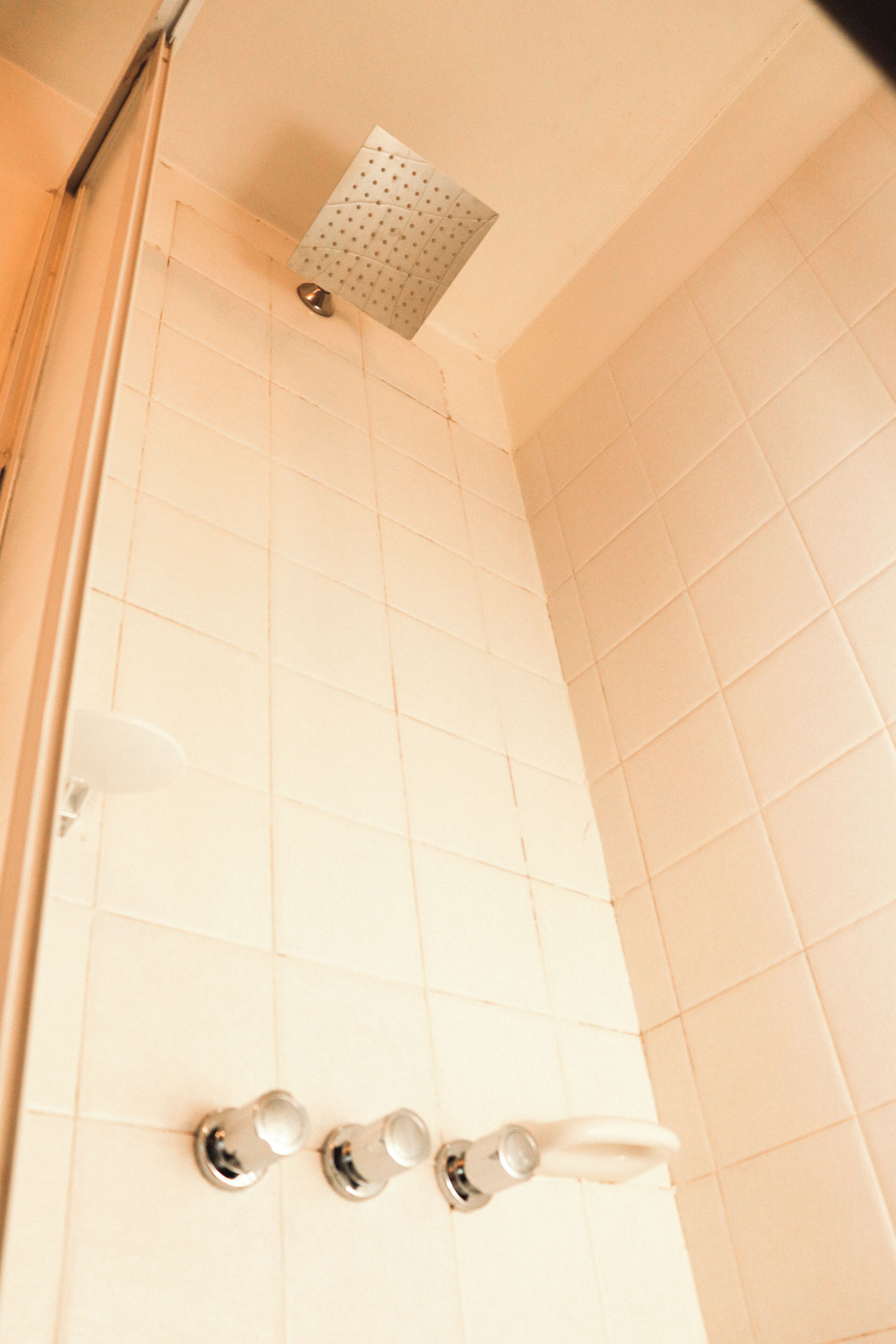 A tiled shower area with a handheld showerhead and a fixed overhead showerhead.