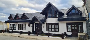 A two-story building with a white facade, dark brown trim, and multiple gabled roofs. - Flor Austral (Ushuaia)
