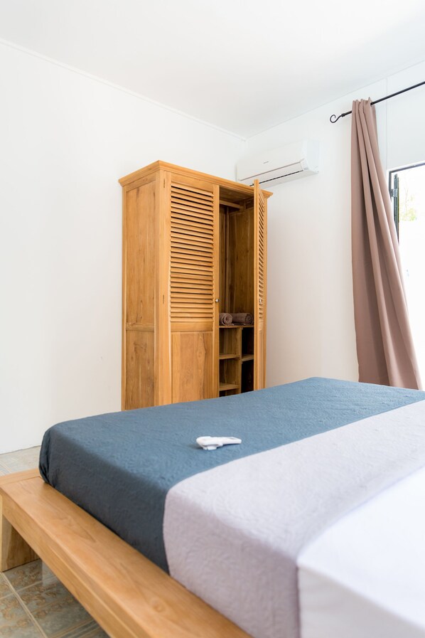 A bedroom with a bed, a wooden wardrobe, and a window with curtains.
