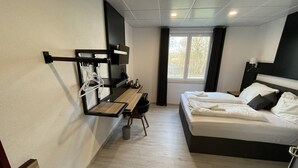 A modern hotel room with a bed, a desk, and a seating area. - Yebs Hotel (Guenzburg)