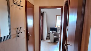 A hallway with tiled flooring, wooden doors, and a ceiling light fixture.