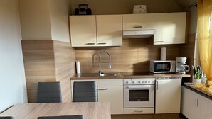 A compact kitchen with a dining table, chairs, a microwave, a coffee maker, and a sink.