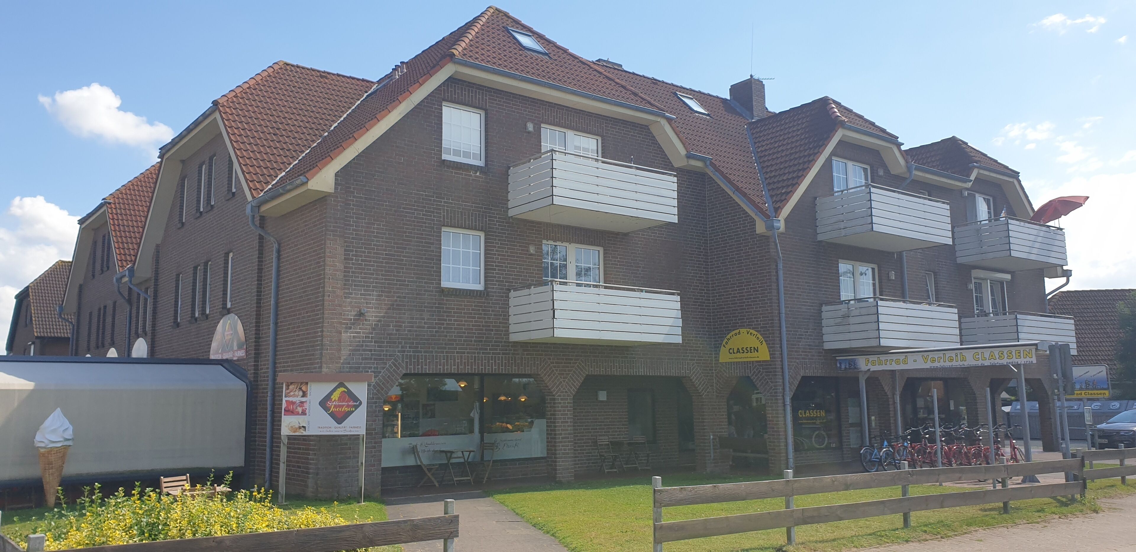 Een meerlaags gebouw met een bakstenen gevel, balkons en een winkel met een bord.